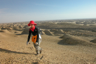 Liu prospecting for bones, teeth, and scales in Qaidam Basin, Tibetan Plateau. The hilly formations in the background are wind-sculptured "clay terraces" called Qaidam yardangs.