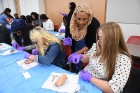 Third-year med student Fatima Elabass (standing, in head scarf) demonstrates technique to (from left) Uju Nwoke, a freshman biological sciences major; Anna Lange, a junior biomedical sciences major; and Whitney Spencer, a senior majoring in biomedical sciences.
