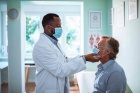 Photo of a provider examining an older man in an exam room. 